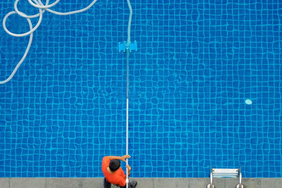 Operario limpiando el fondo de una piscina comunitaria